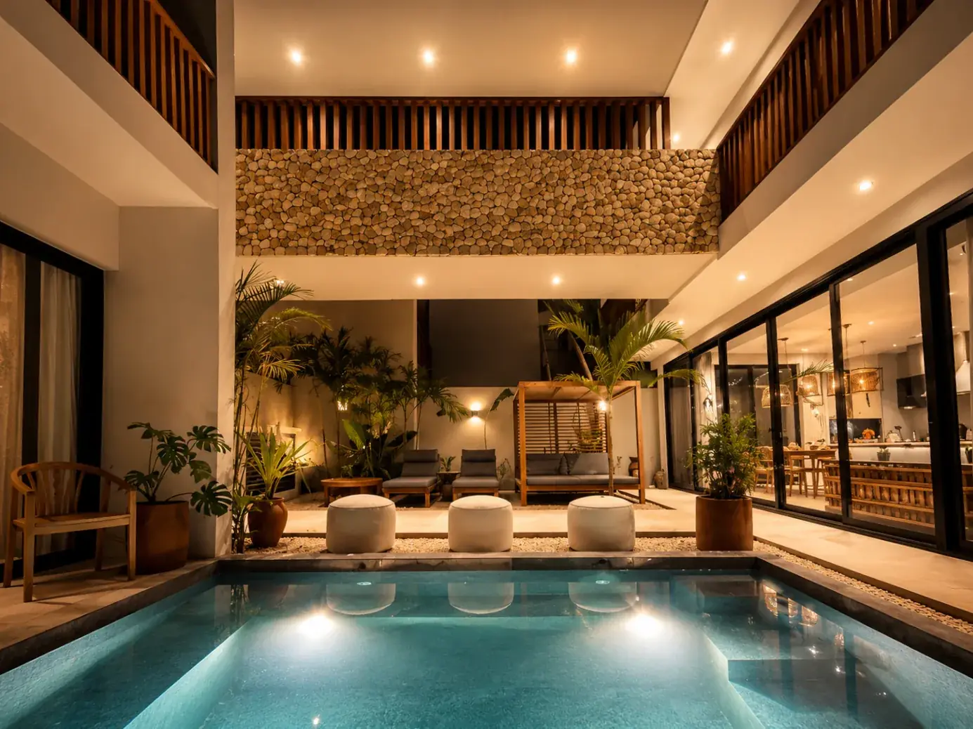 The courtyard pool lit at dusk, seen from the double-height living room