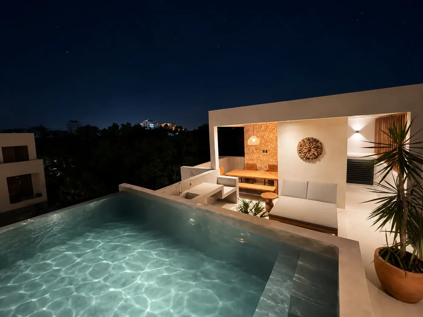 The rooftop infinity pool lit at night above the Tulum treeline